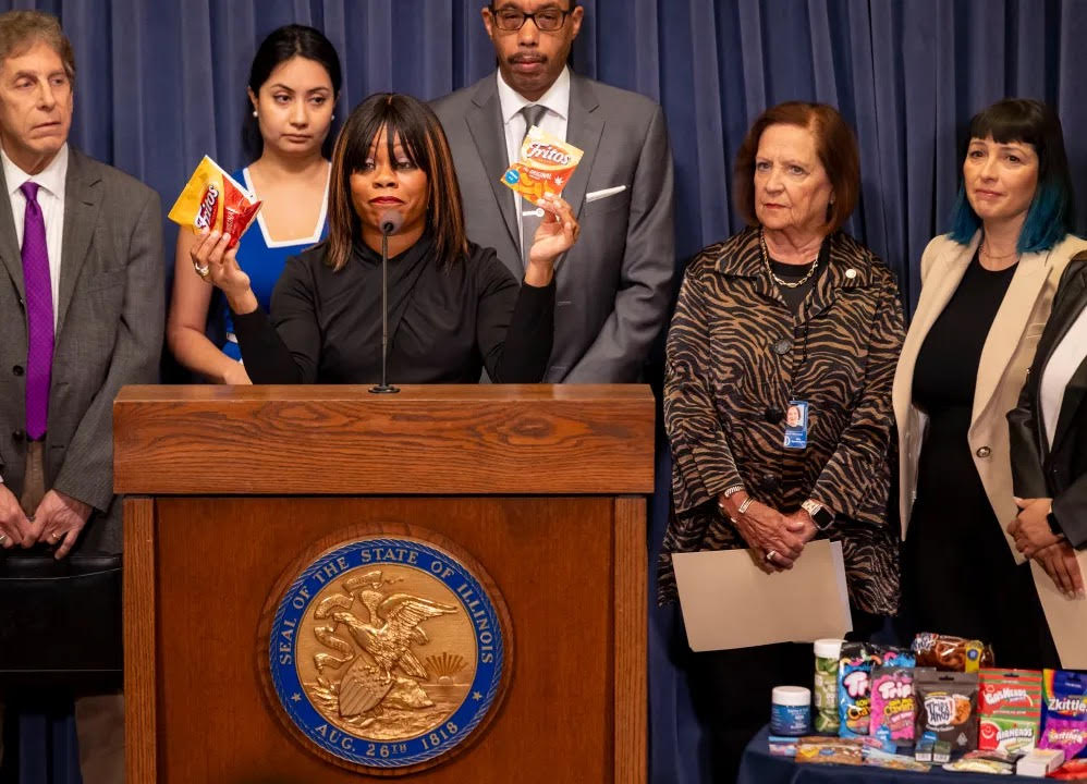 Tiffany Chappel Ingram holds up a bag of Fritos branded-corn chips and another bag of corn chips that mimics the Frito chips packaging.